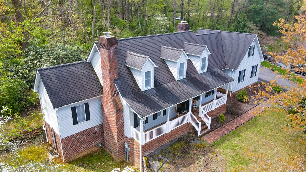 Drone aerial of a two-story home with a wraparound porch, shot for a Johnson City listing