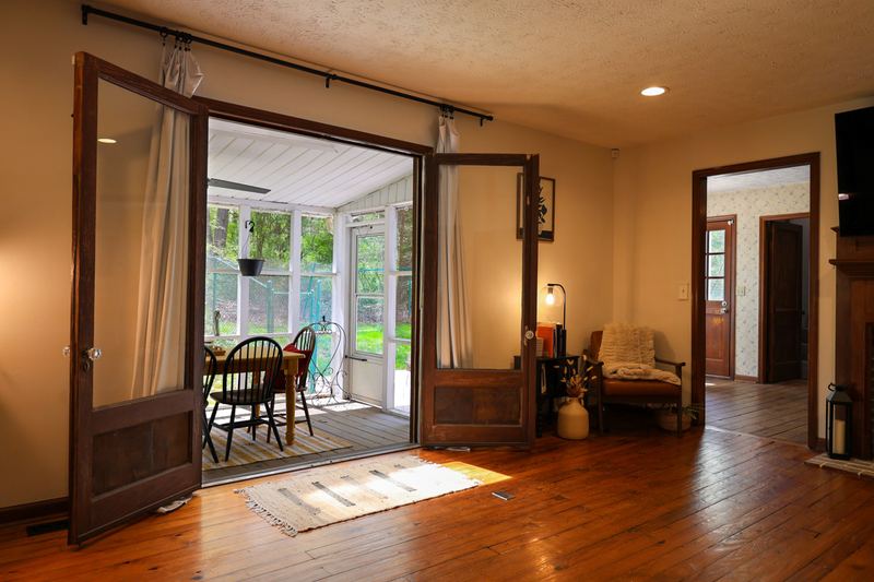 Hardwood dining area opening through French doors to a sunroom