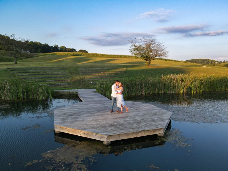 Engaged couple on a wooden dock over a pond