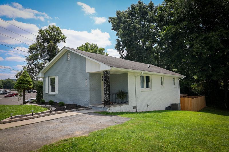 Front exterior of a light gray ranch home with a green lawn