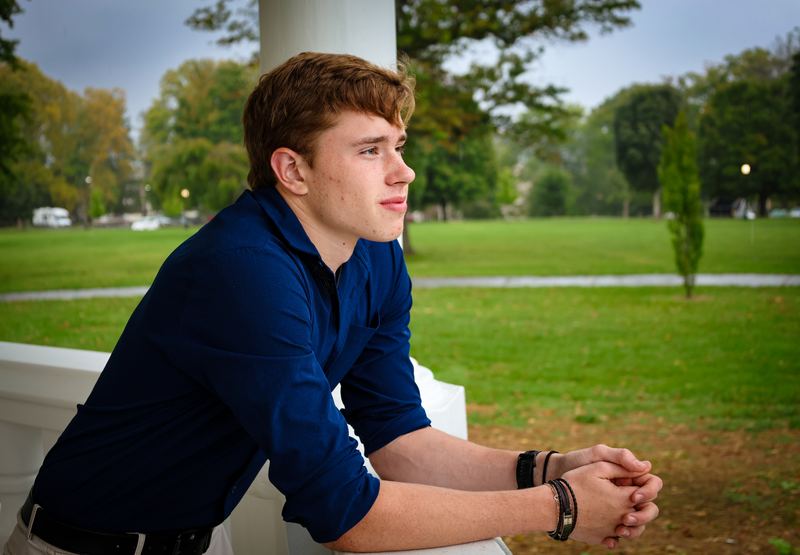 Senior portrait of a young man leaning on a white railing